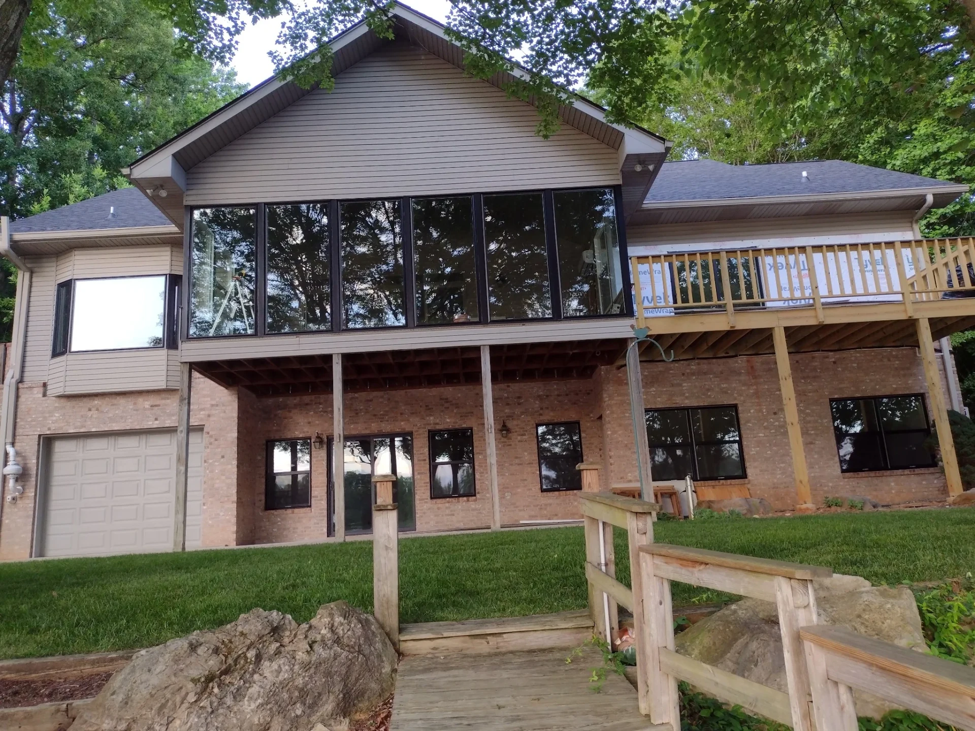 Rear of a home with a wall of large dark-framed windows installed, work in progress